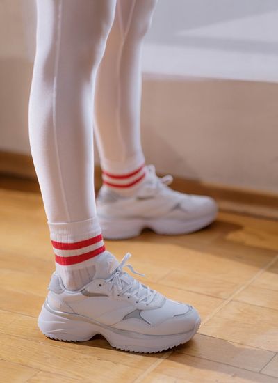 A close-up shot of athletic shoes on a wooden floor, suggesting readiness for exercise.