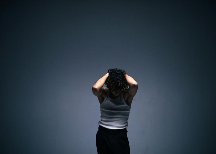 Person in light athletic wear performing a fluid cardio movement in a bright, spacious room.